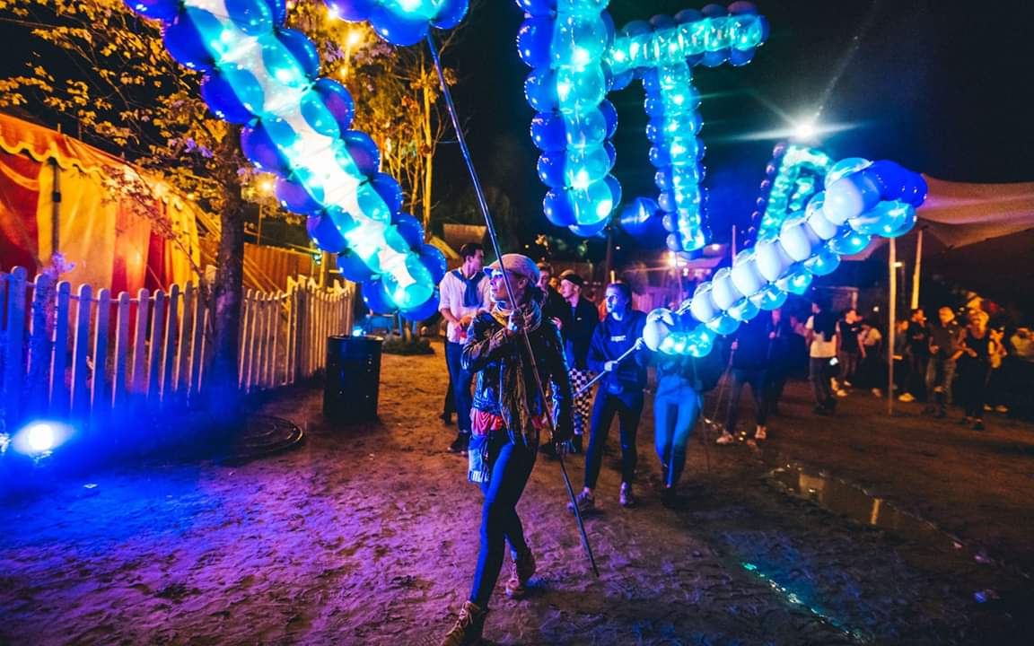 Spellbound LED balloon letters spelling DIMITRI carried through the crowd at night at Thuishaven in Amsterdam (2019)