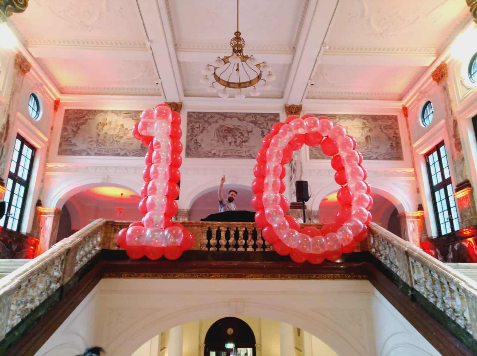 Custom balloon decoration with large red LED-lit number 10 on a classical balcony with DJ at an unknown venue (2019)